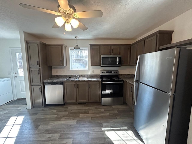 kitchen with a textured ceiling, wood finished floors, appliances with stainless steel finishes, and a sink