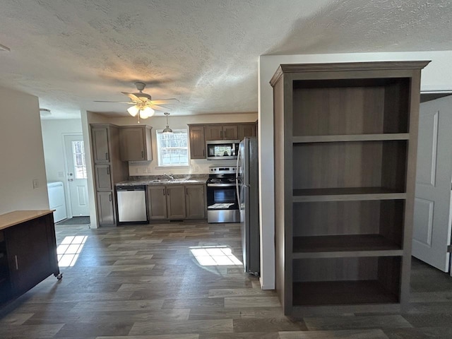 kitchen featuring a sink, appliances with stainless steel finishes, a textured ceiling, a ceiling fan, and dark wood-style flooring