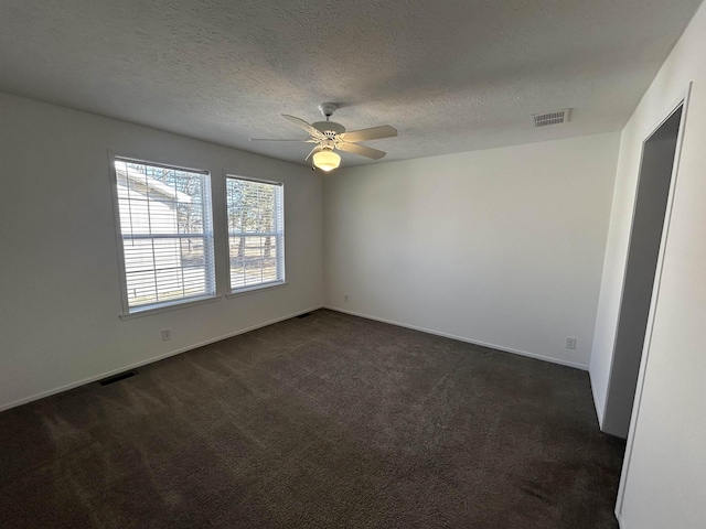 unfurnished room featuring visible vents, dark carpet, a textured ceiling, and a ceiling fan