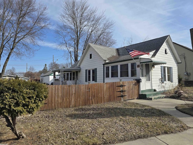 bungalow-style home with a fenced front yard and a shingled roof