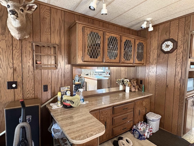 kitchen featuring light countertops, wooden walls, and brown cabinetry