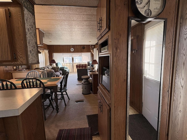 dining room featuring wooden walls and dark carpet