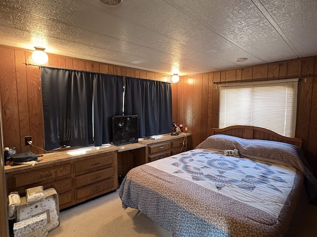 bedroom with light carpet, a textured ceiling, and wood walls