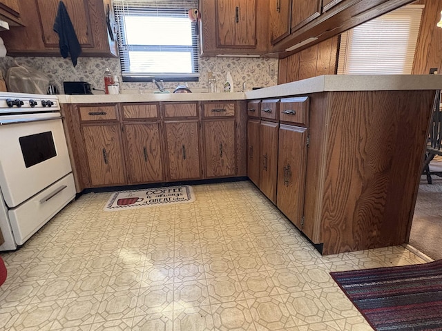 kitchen with tasteful backsplash, light floors, light countertops, a peninsula, and electric range