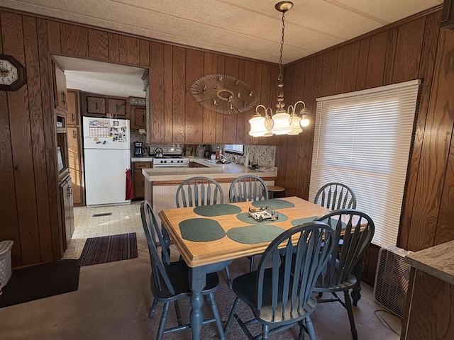 dining space featuring a notable chandelier and wooden walls