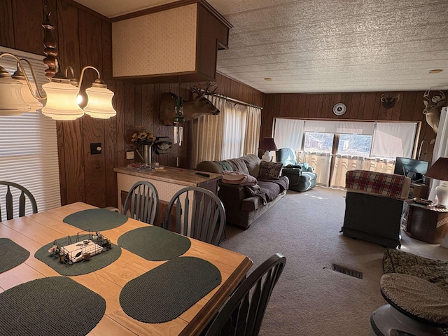 dining room featuring visible vents, carpet, and wood walls