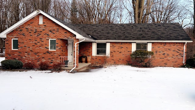 view of front facade with brick siding and a shingled roof