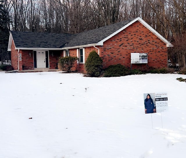 view of front of home featuring brick siding and roof with shingles