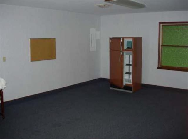 unfurnished room featuring dark colored carpet and baseboards