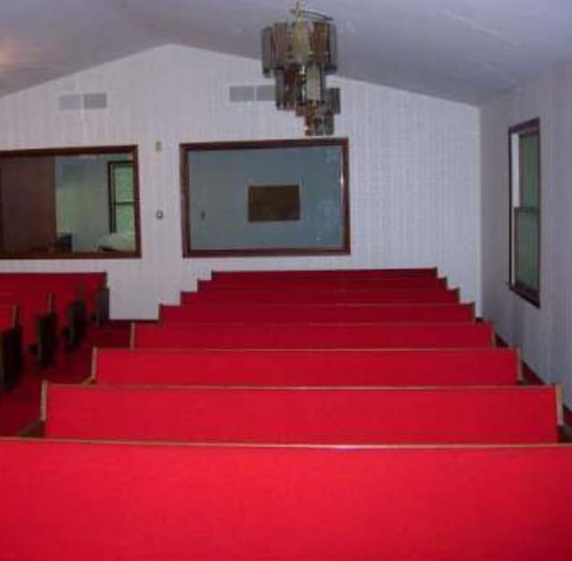 home theater room featuring vaulted ceiling and a notable chandelier