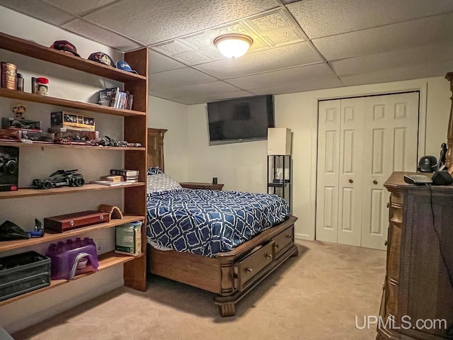 bedroom featuring a closet, a drop ceiling, and light colored carpet