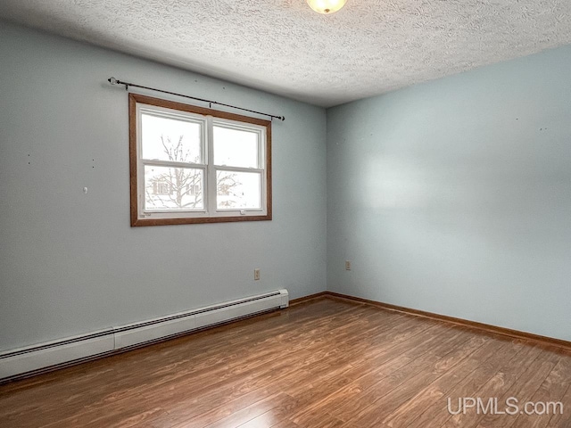 empty room with baseboards, baseboard heating, wood finished floors, and a textured ceiling