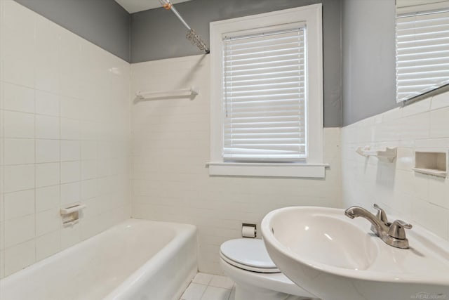 full bathroom with bathing tub / shower combination, a sink, tile walls, toilet, and tile patterned floors