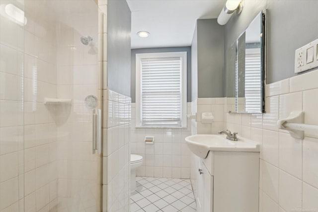 full bath with vanity, a stall shower, tile patterned floors, toilet, and tile walls