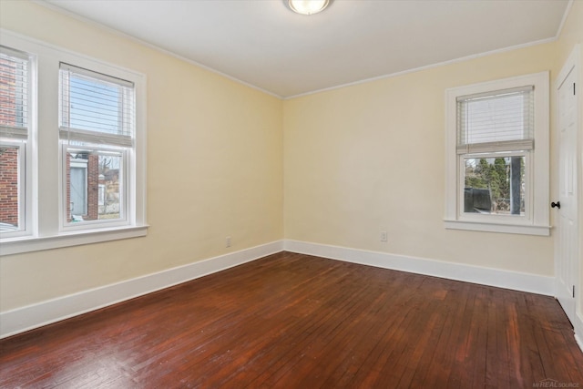 spare room featuring ornamental molding, baseboards, and dark wood-style flooring