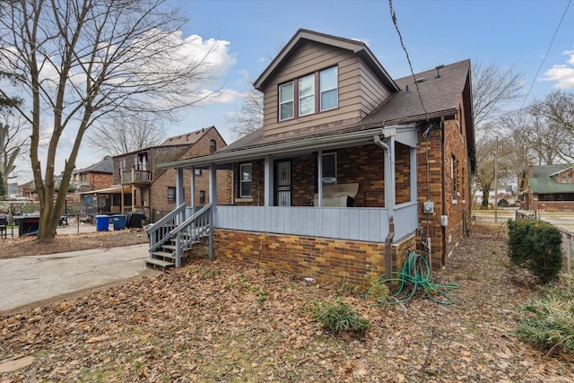 bungalow with a porch, fence, and brick siding