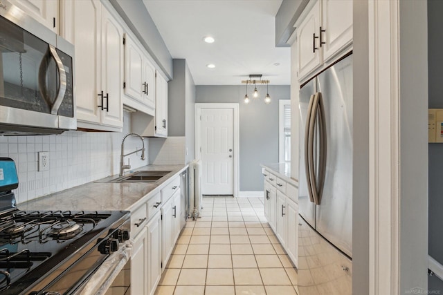 kitchen with tasteful backsplash, stainless steel appliances, light tile patterned flooring, white cabinetry, and a sink