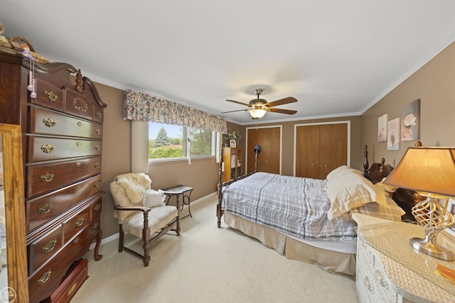 carpeted bedroom with ceiling fan, baseboards, multiple closets, and ornamental molding