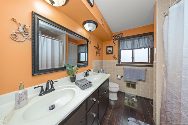 full bathroom featuring tile walls, wood finished floors, visible vents, and a sink