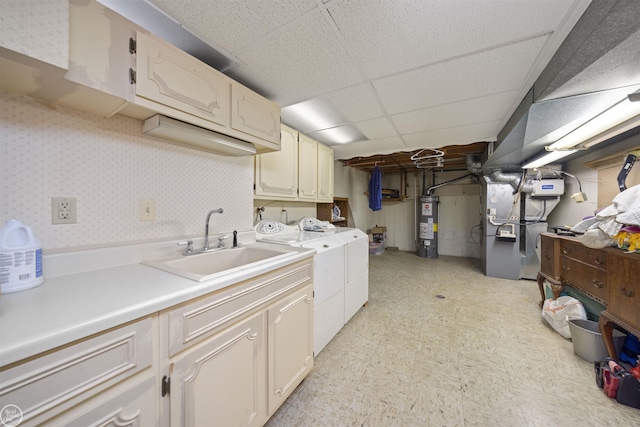 laundry area with wallpapered walls, washer and clothes dryer, gas water heater, cabinet space, and a sink