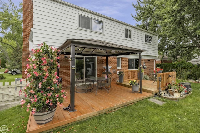 back of house with brick siding, fence, a gazebo, a deck, and a yard