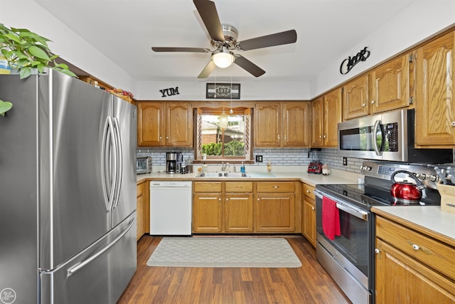 kitchen featuring a sink, stainless steel appliances, dark wood-style floors, and light countertops