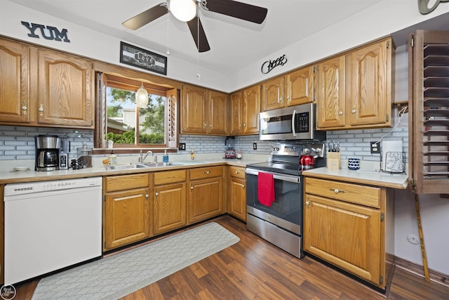 kitchen with a sink, light countertops, brown cabinets, appliances with stainless steel finishes, and dark wood-style flooring