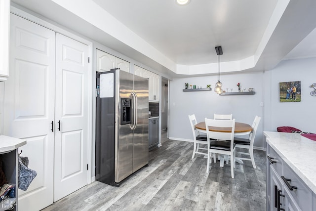 dining room with baseboards, a raised ceiling, and light wood finished floors