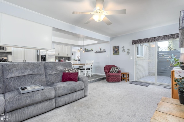 carpeted living area featuring ceiling fan, baseboards, and ornamental molding