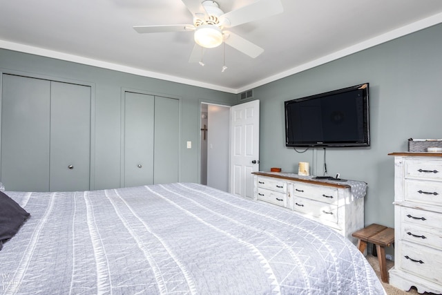 bedroom with visible vents, a ceiling fan, and multiple closets