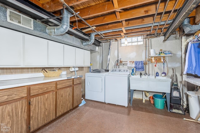 laundry room with washer and dryer, visible vents, cabinet space, and a sink