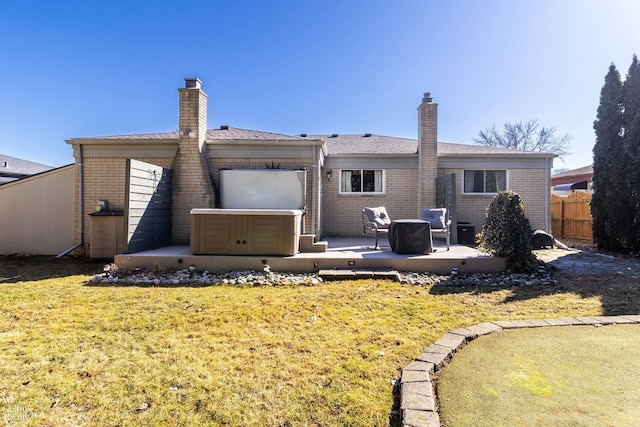 back of house featuring a chimney, a hot tub, a patio, and fence