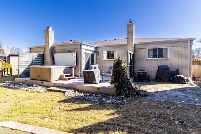 rear view of house featuring a patio, brick siding, and a chimney