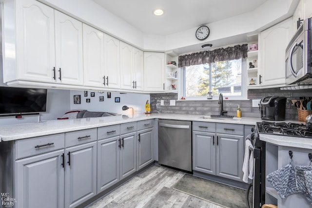 kitchen featuring a sink, open shelves, stainless steel appliances, and gray cabinetry