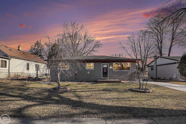 view of front of property featuring a yard, brick siding, and fence