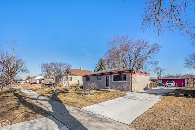 view of front of home featuring brick siding, driveway, an outbuilding, and a front yard