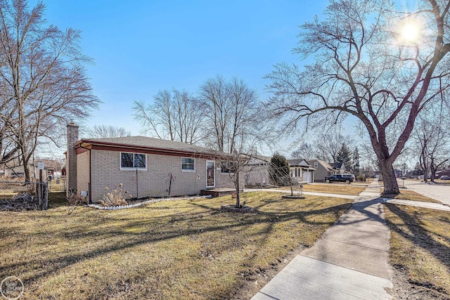 exterior space featuring a yard, brick siding, a chimney, and fence