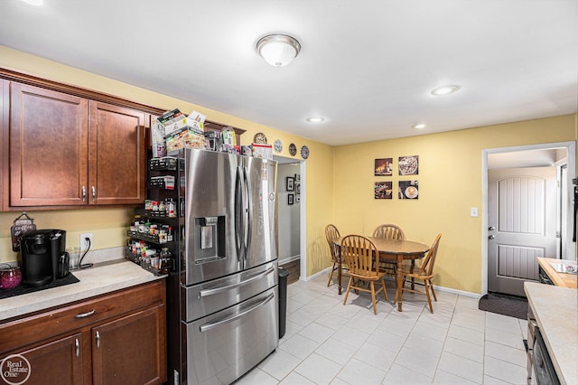 kitchen featuring baseboards, light tile patterned flooring, recessed lighting, stainless steel fridge with ice dispenser, and light countertops