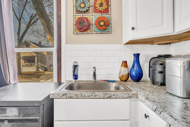 kitchen featuring white cabinetry, light countertops, decorative backsplash, and a sink