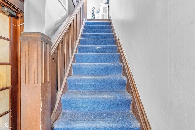 stairway featuring baseboards and a textured wall