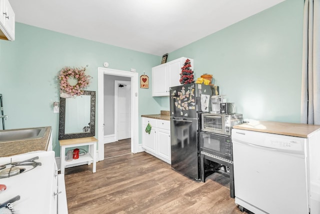 kitchen featuring a sink, white cabinetry, freestanding refrigerator, white dishwasher, and light wood finished floors