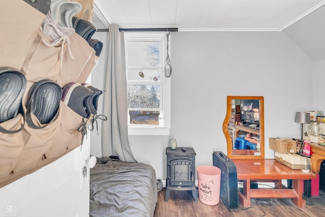 bedroom with lofted ceiling, a wood stove, wood finished floors, and ornamental molding