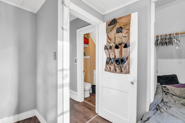 hall featuring wood finished floors, baseboards, and ornamental molding