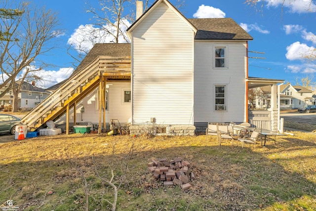 view of side of property with a shingled roof, a carport, stairway, and a chimney