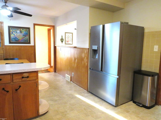 kitchen with visible vents, wooden walls, a wainscoted wall, light countertops, and stainless steel fridge