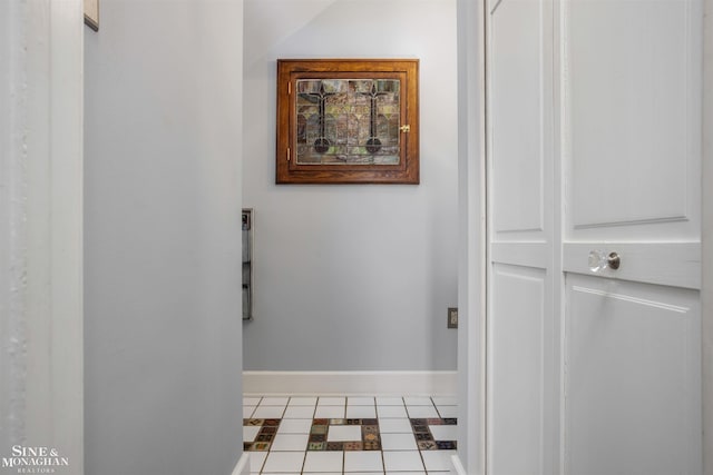 hallway featuring tile patterned floors and baseboards