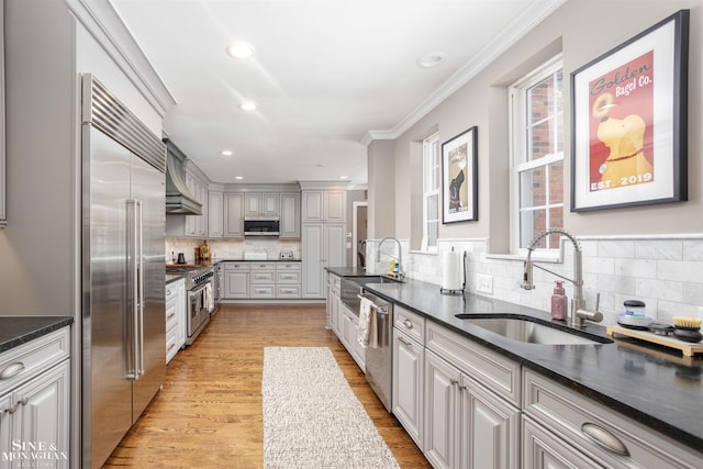 kitchen featuring a sink, dark countertops, high end appliances, and ornamental molding