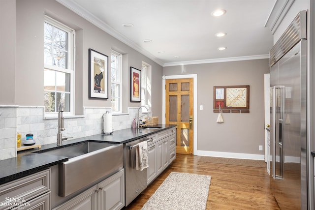 kitchen featuring plenty of natural light, ornamental molding, stainless steel appliances, and a sink