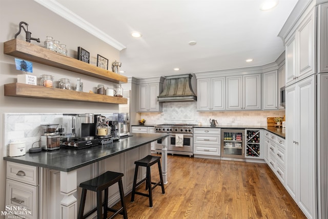 kitchen with custom range hood, dark countertops, wine cooler, range with two ovens, and decorative backsplash