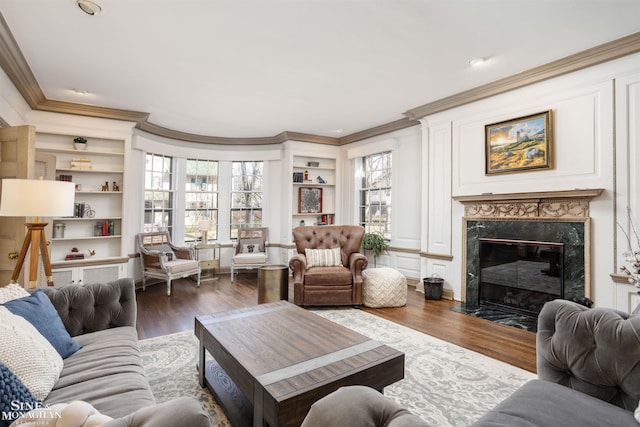 living room featuring ornamental molding, built in shelves, wood finished floors, and a premium fireplace